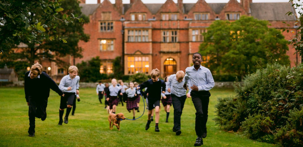 Happy pupils running outside the front of Port Regis Prep school in Dorset