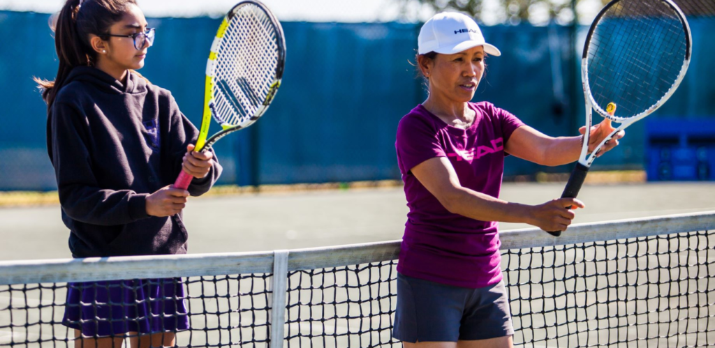 A female teacher teaching a pupil to play tennis